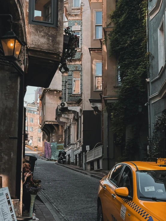 an alleyway in a city with a taxi and pedestrians