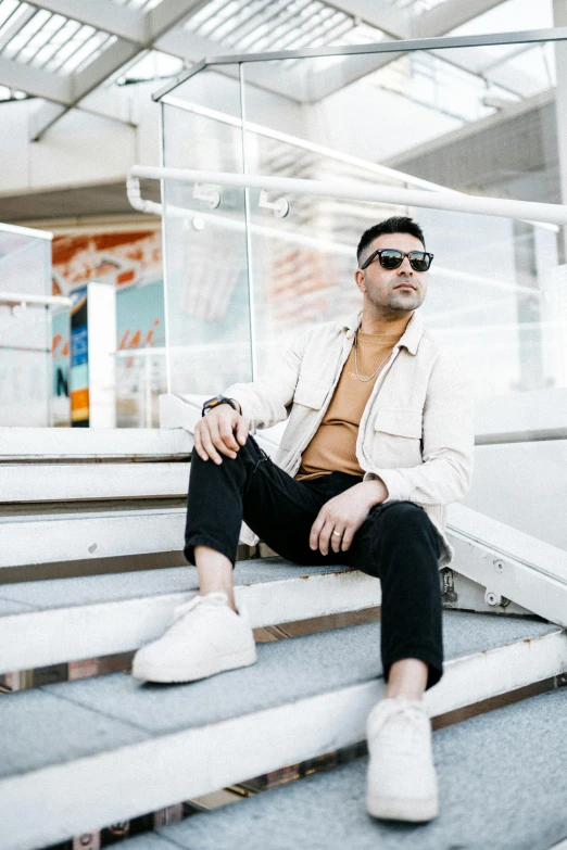 a man wearing sunglasses sitting on stairs with his feet propped up