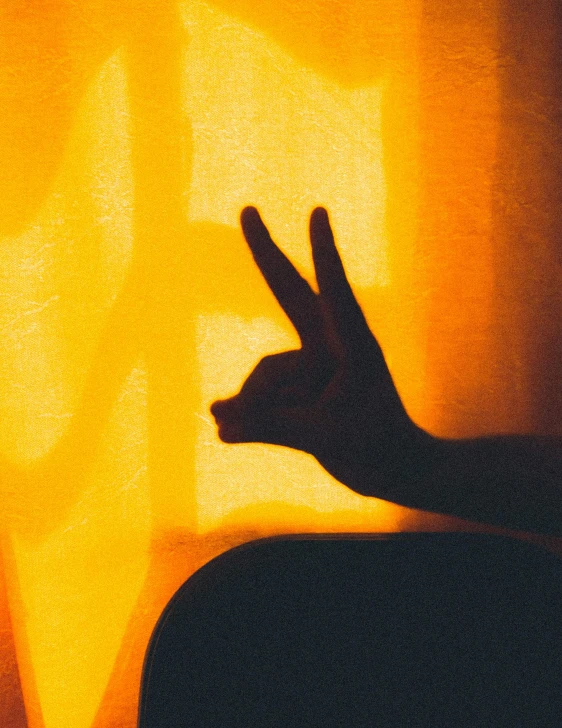 the silhouette of a person pointing to a yellow light