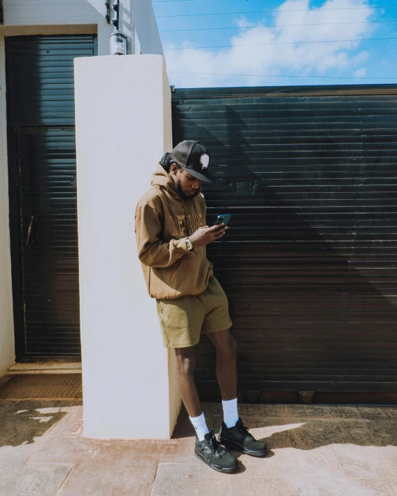 a man with ear buds is standing with his cellphone by the wall