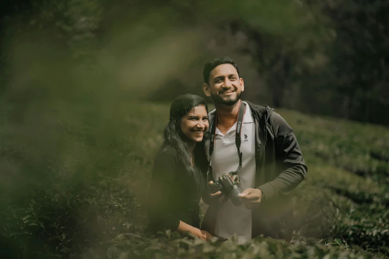 couple smiling for po taking in field with trees