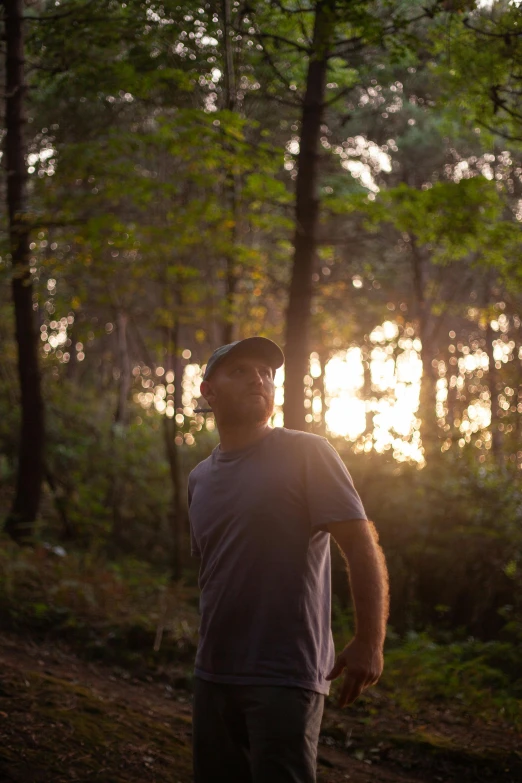 the man looks away from the sun in a wooded area