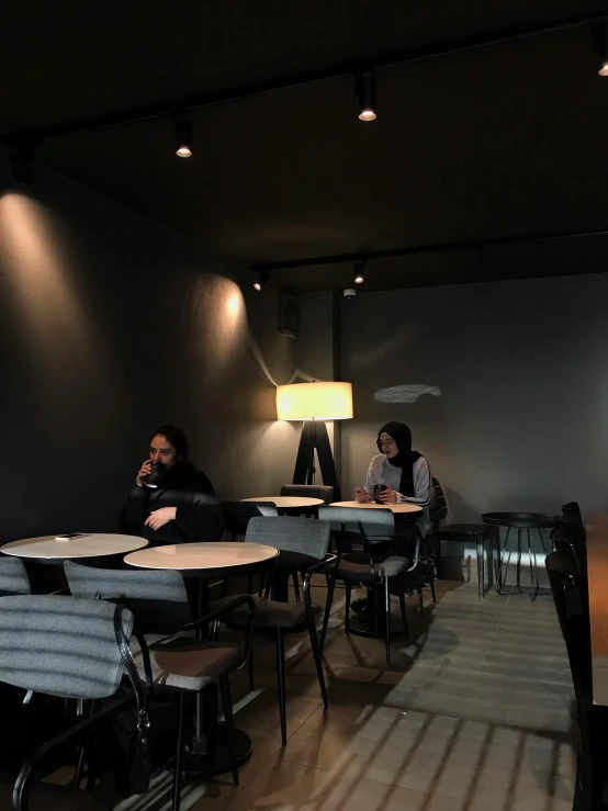 a couple sitting in a large room with light fixtures