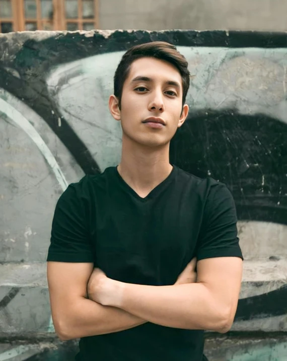 a man posing with his arms crossed in front of a painting