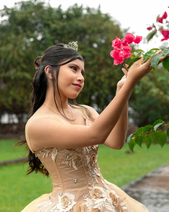 a girl in a dress holding a nch with red flowers on it