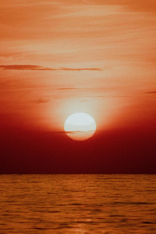 a sunset over the ocean with clouds in the sky