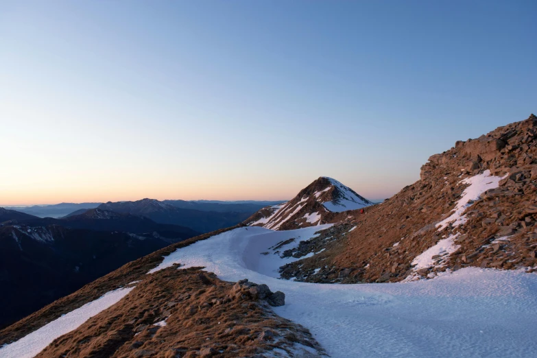 an mountain peak with snow and no leaves is surrounded by a blue sky