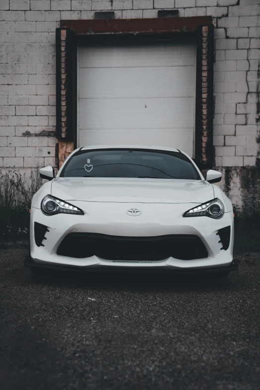 a white sports car is parked outside a garage