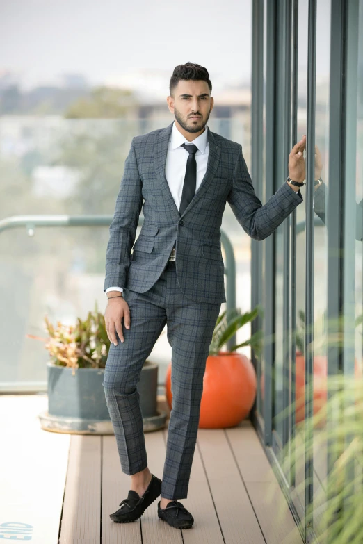 the man wearing a suit standing against a glass wall