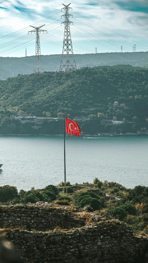 a red flag flying in front of a large lake