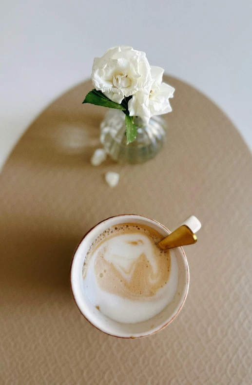 a white vase of flowers is sitting next to a cup