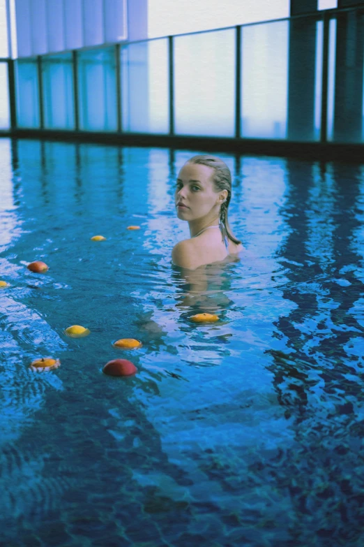 a woman swimming in an indoor pool full of balls