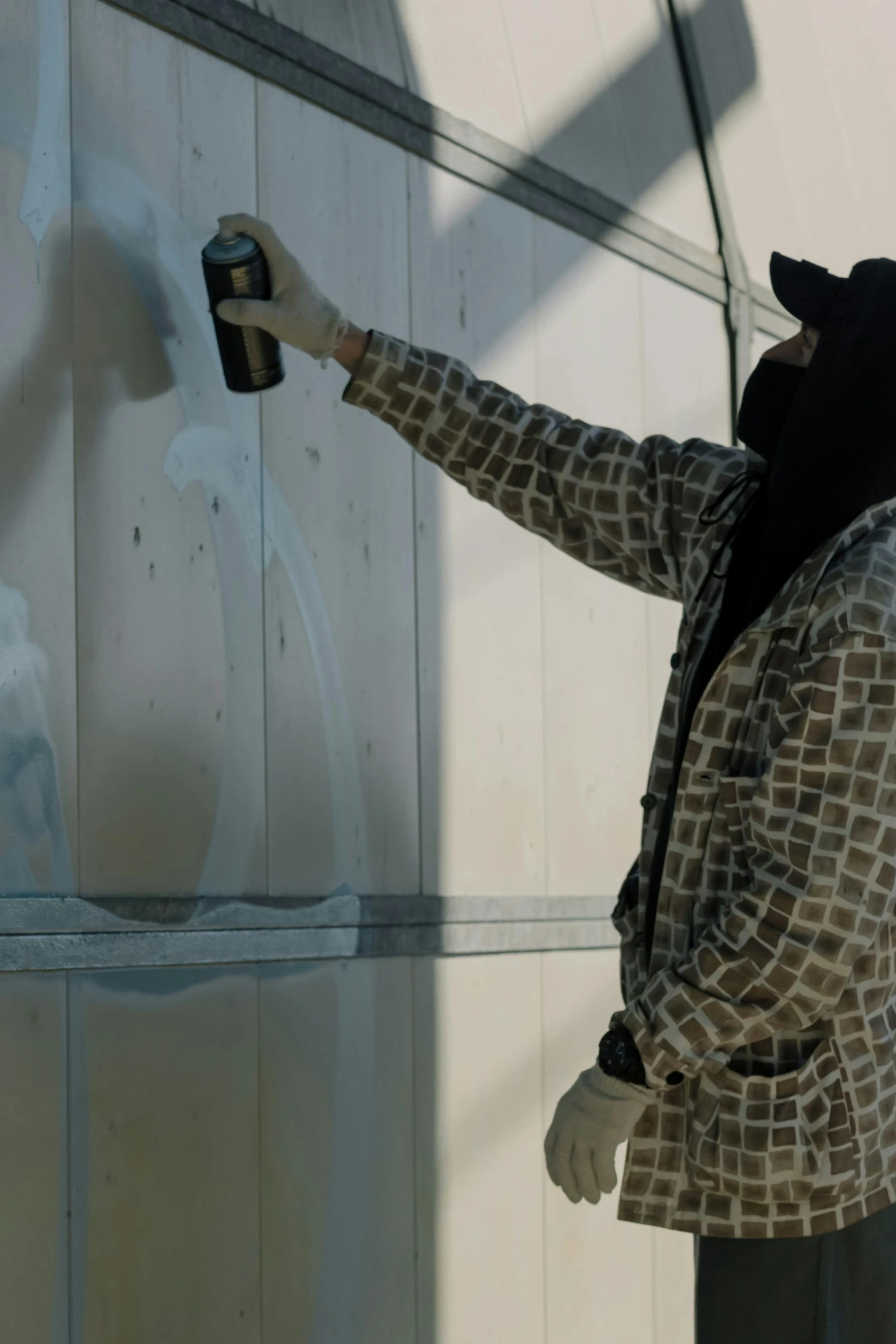 a person in mask spraying up graffiti on a white wall