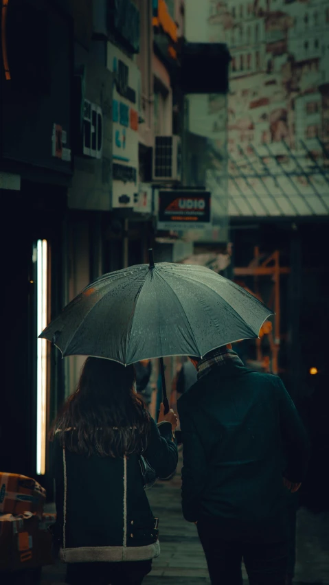 two people walking down a sidewalk while holding umbrellas