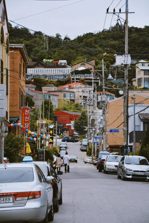 a city street with traffic passing by and houses on the hill in the background