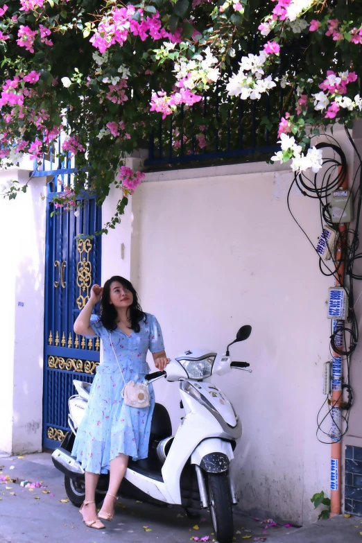 a woman in dress and heels standing next to white scooter