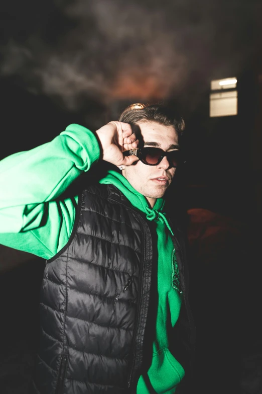 a man wearing sunglasses and a green sweater standing