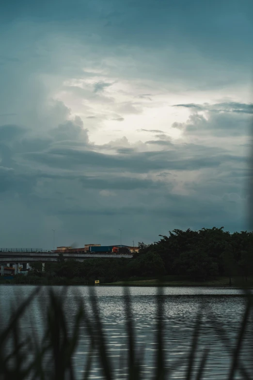 train riding on railroad over a river under a cloudy sky