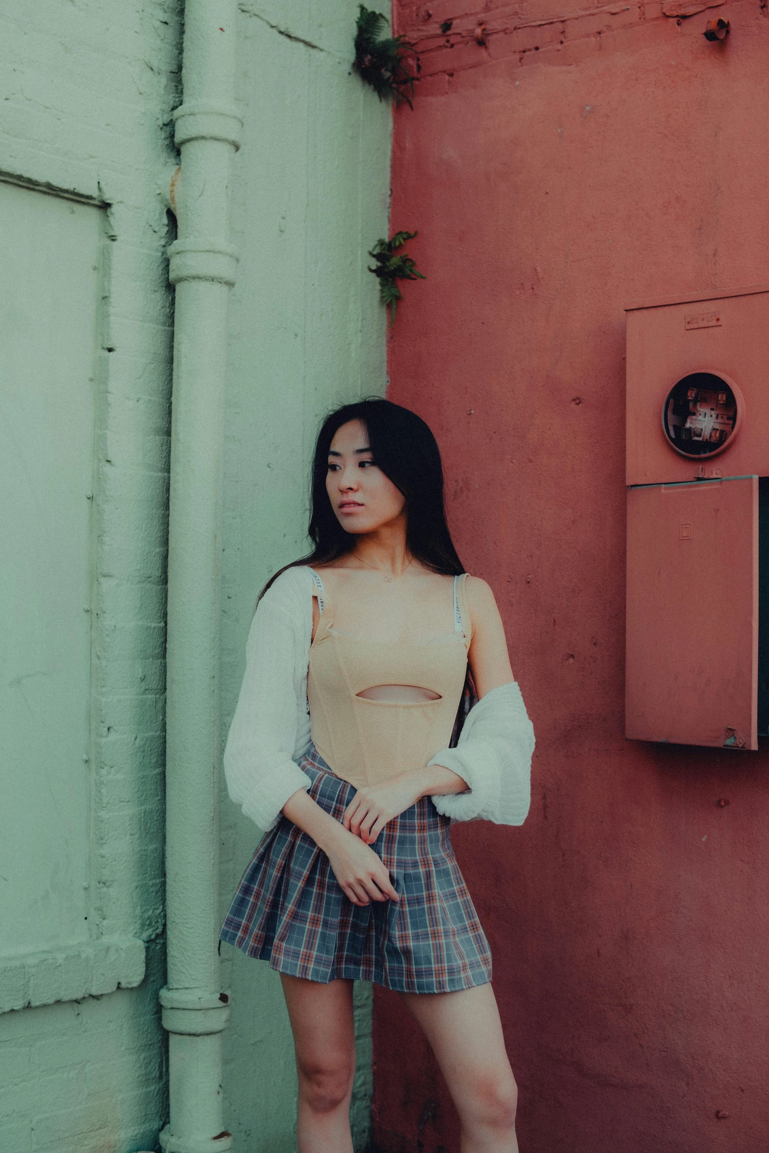 the young woman is posing by the red building