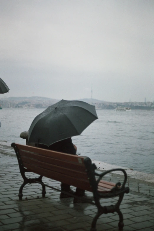 people sitting on park bench with an umbrella