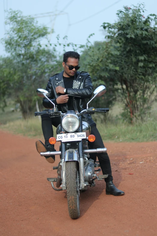 a man in black sitting on the back of a motorcycle