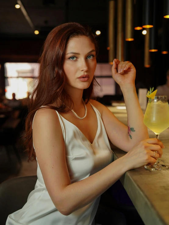 a woman sitting at a table with a glass of alcohol
