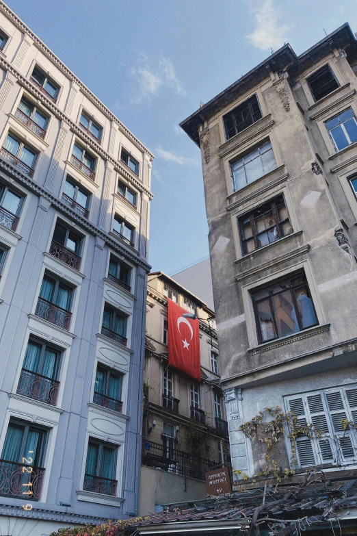 two gray buildings with two red flags hanging off the balconies