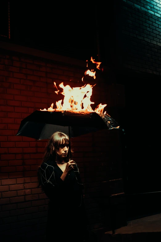 a woman holds up an umbrella that is on fire