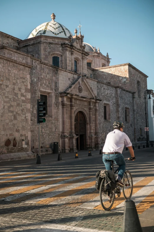 the man is riding his bike past the church