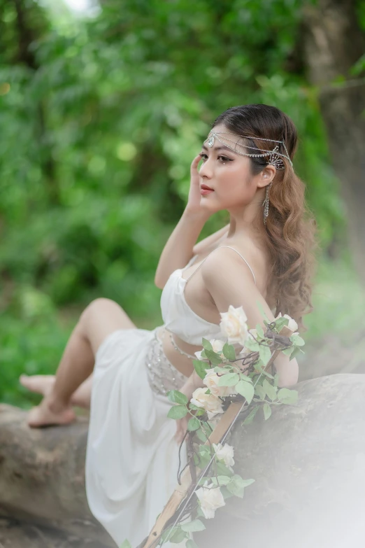 a woman in a white dress is sitting on a rock