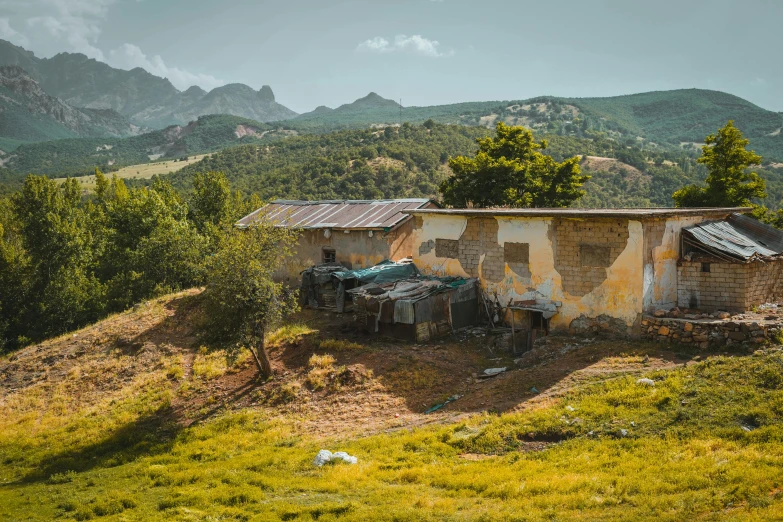 a dilapidated building on a hill overlooking some mountains