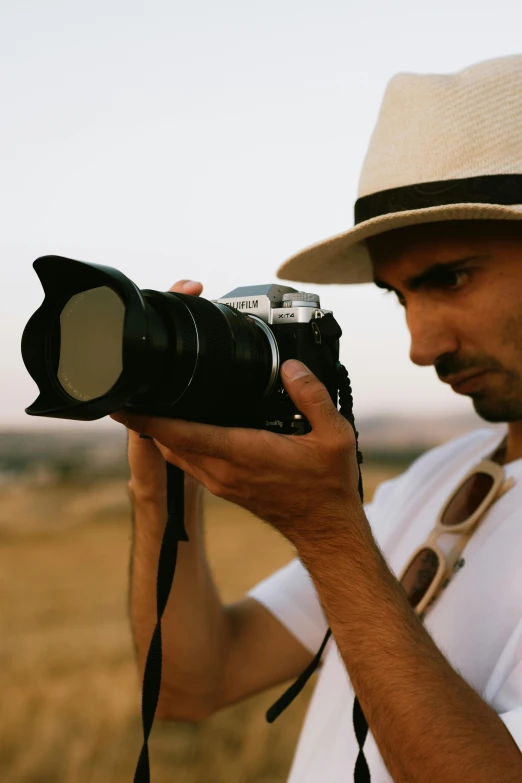 a man with hat holding a camera on his neck