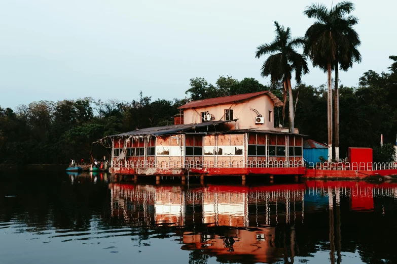 a red house sitting next to palm trees on top of a lake