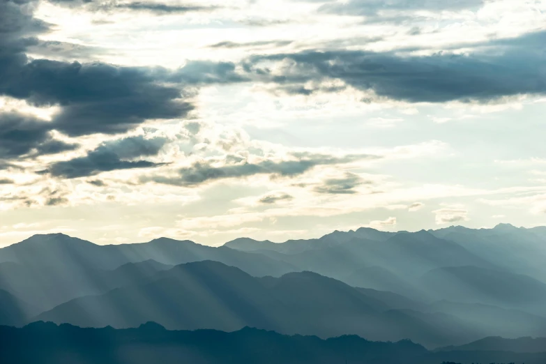 a dark and cloudy sky with mountain ranges in the background