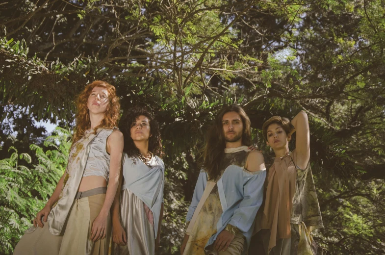 four people posing in front of trees in the sun