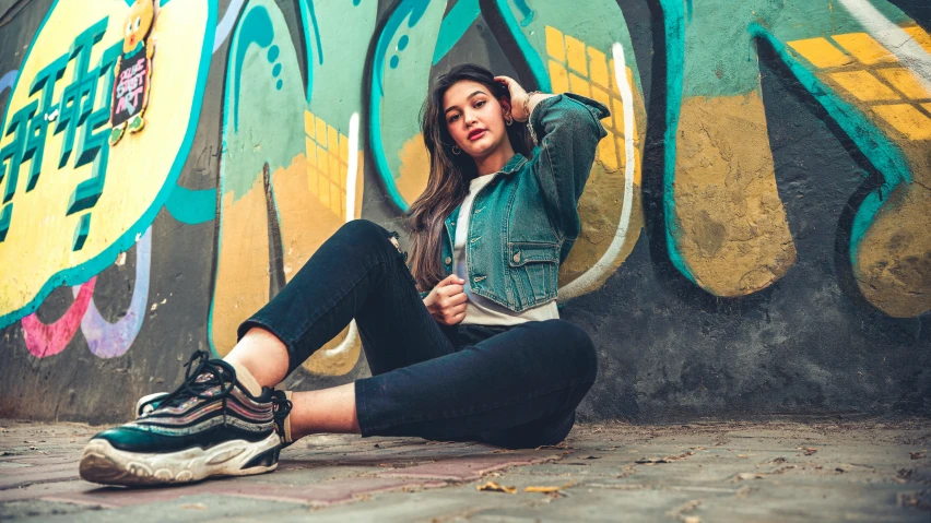 a woman sitting against graffiti and looking off to the side