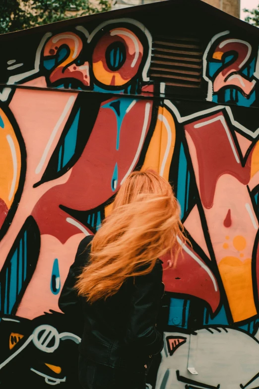 a woman is walking by a wall that has graffiti on it