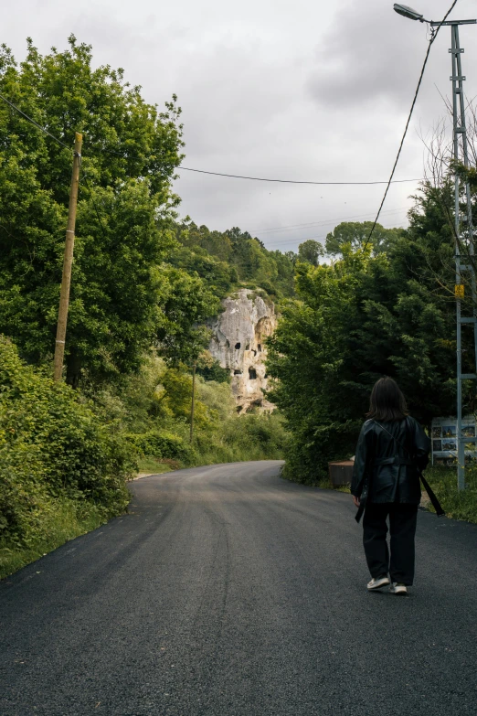 a person walking down a road towards trees