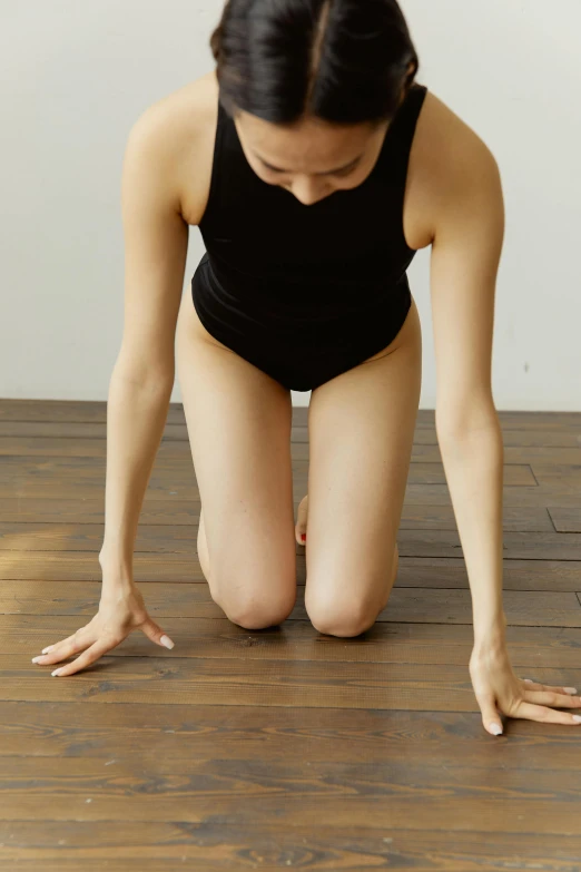 a woman kneeling down on top of a wooden floor