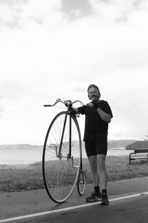 the man is standing near the bicycle in the road