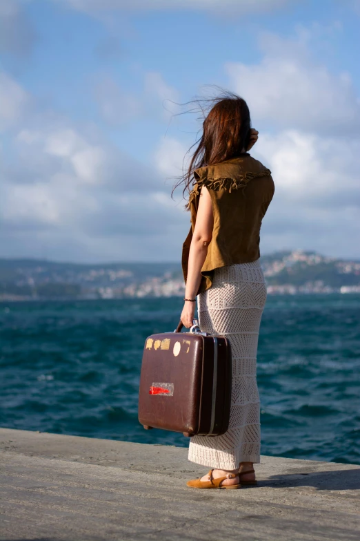 a woman with a suitcase looking out over the ocean