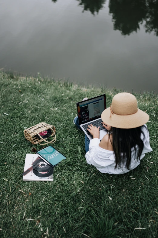 a woman on grass using her laptop on her lap