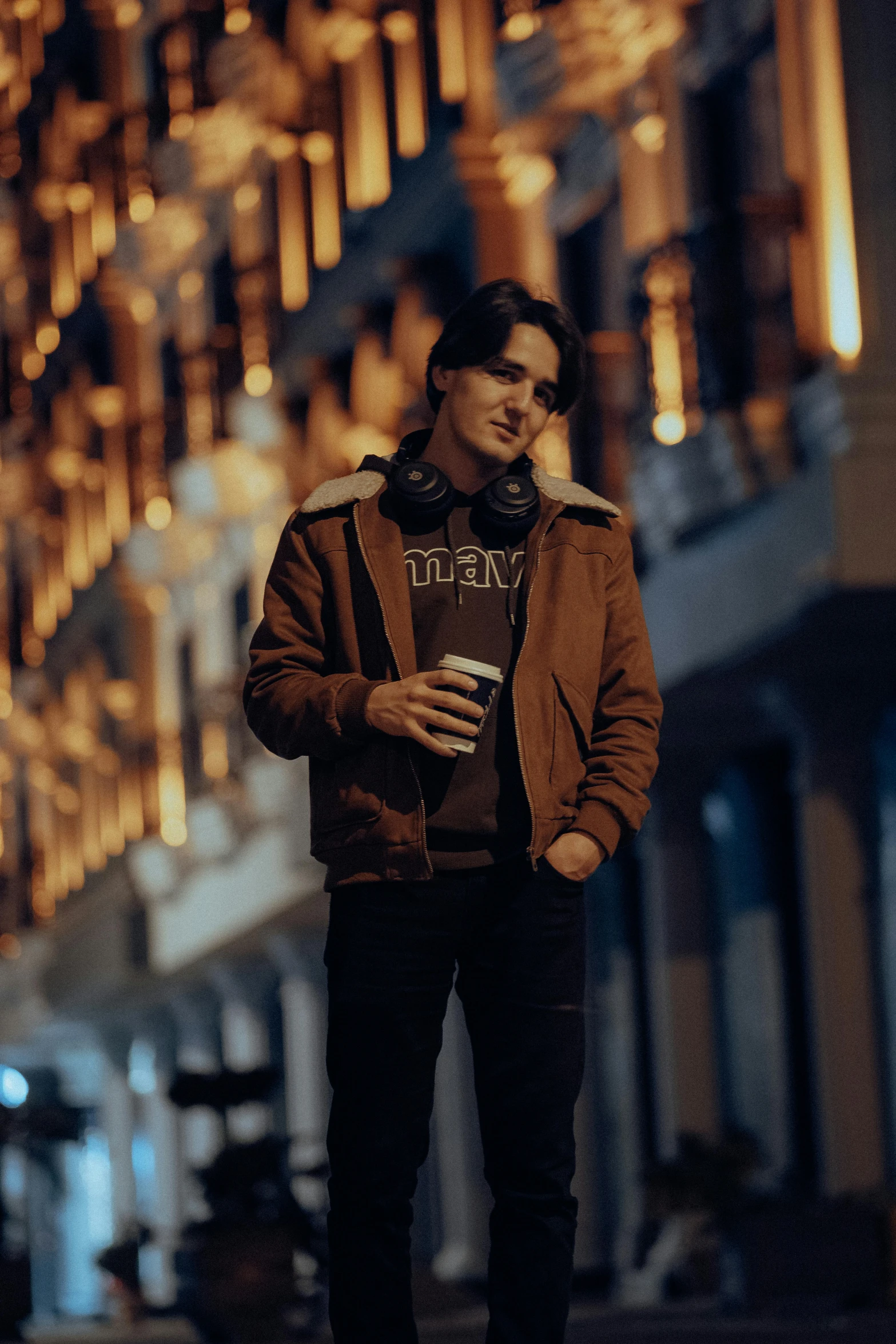 a young man standing on the sidewalk with a cup