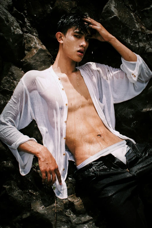 a man in white shirt sitting on top of a rock