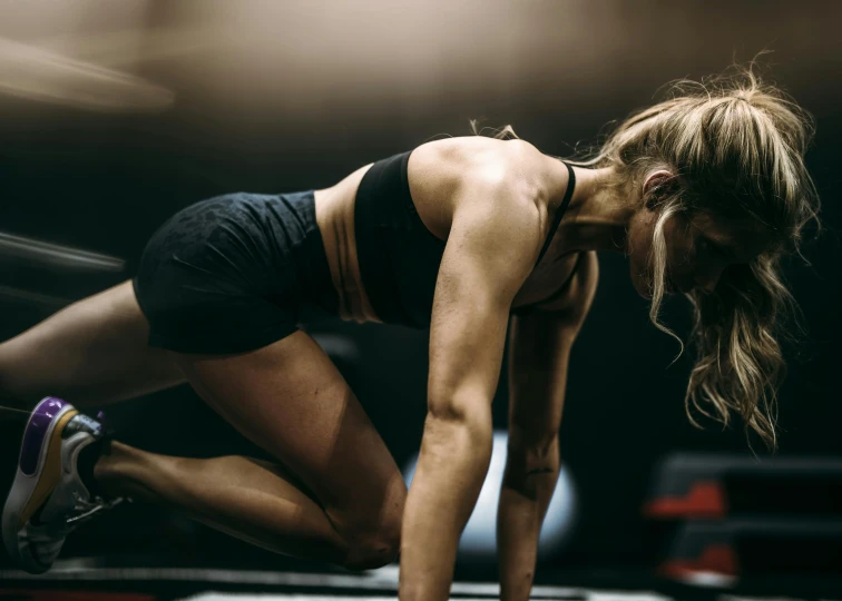 a woman kneeling down on the floor in a gym