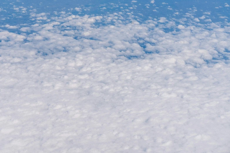 a plane flying high up in the sky with clouds