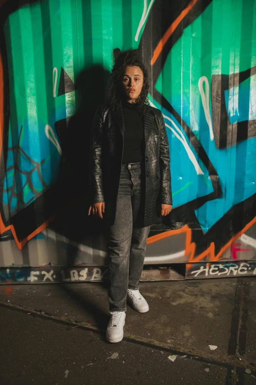 a girl stands in front of graffiti and the word exit