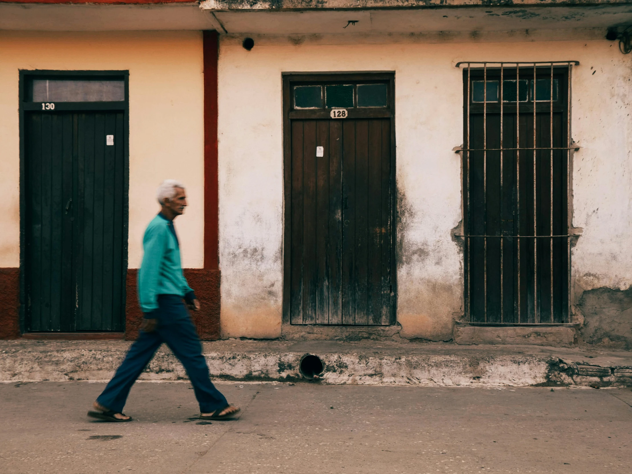 a man walks down a sidewalk past two buildings