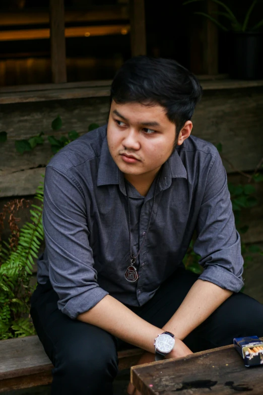 man sits on a bench in front of greenery