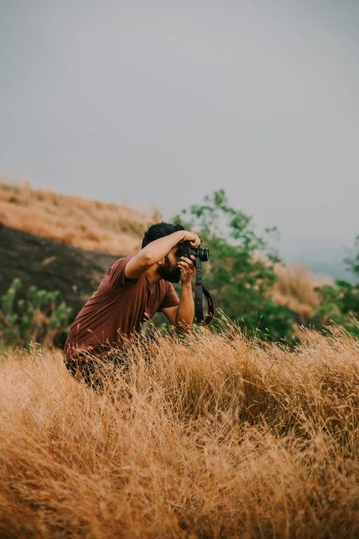 a man taking pictures in high grass with his camera